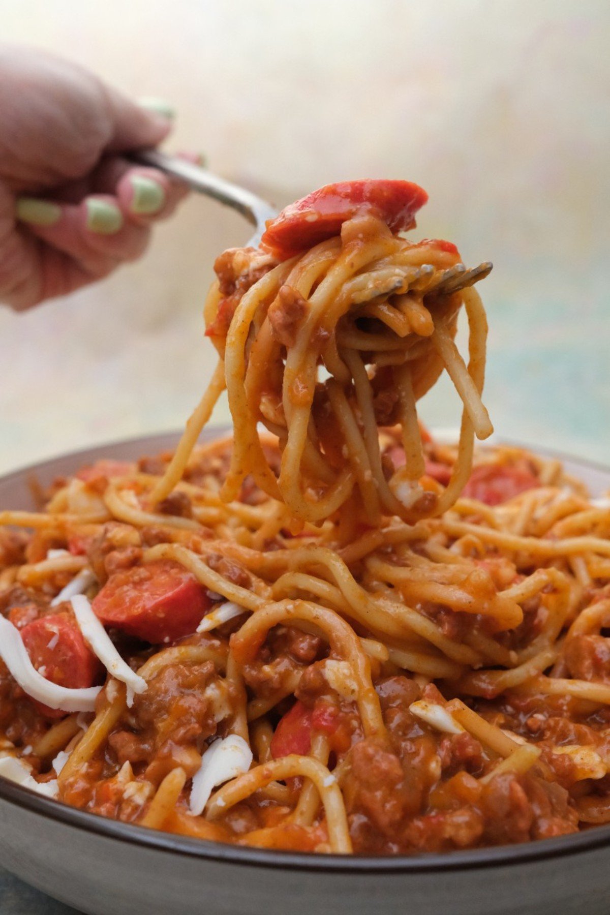 Filipino spaghetti in a bowl, with a fork lifting a portion.