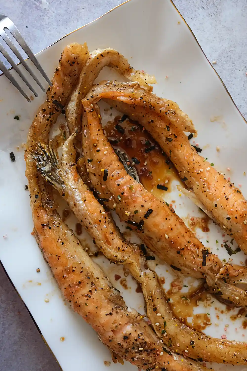 Air-fried salmon belly arranged on a white plate with teriyaki glaze and furikake.
