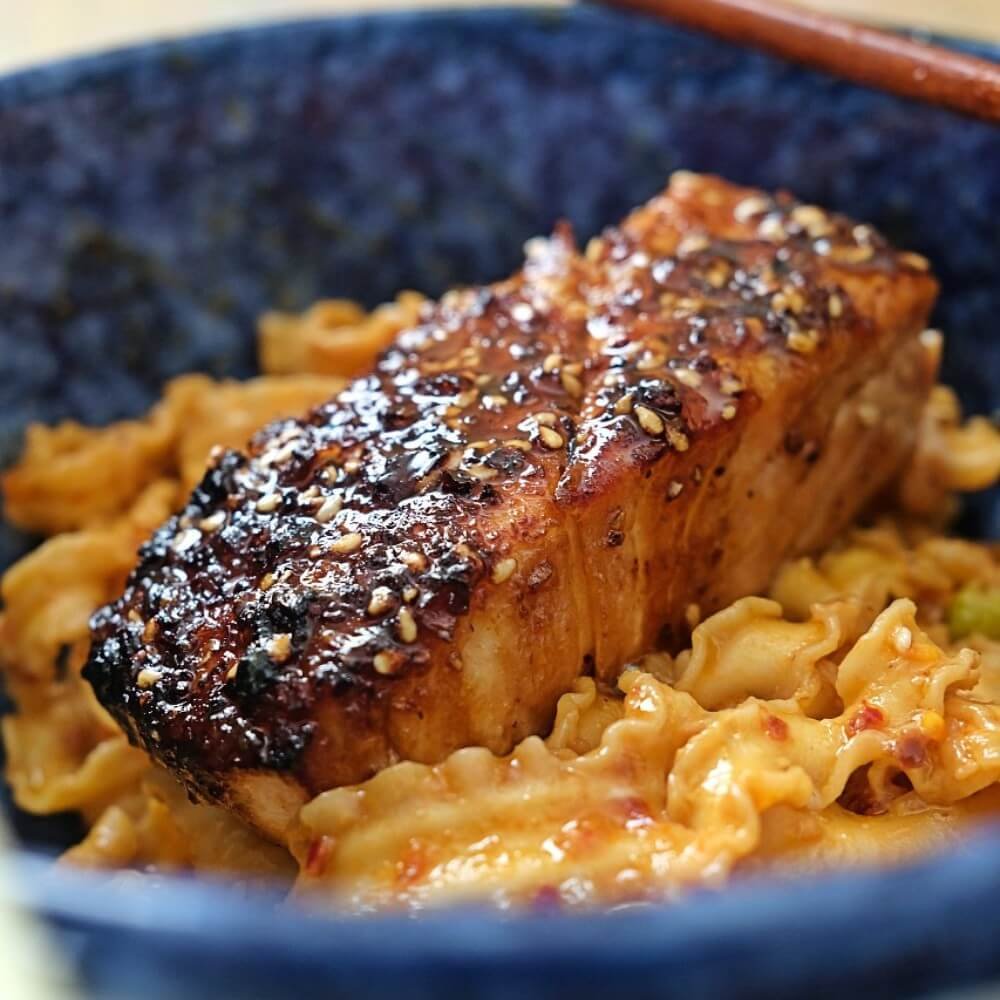 Air fryer teriyaki salmon fillet glazed with sauce served over noodles.