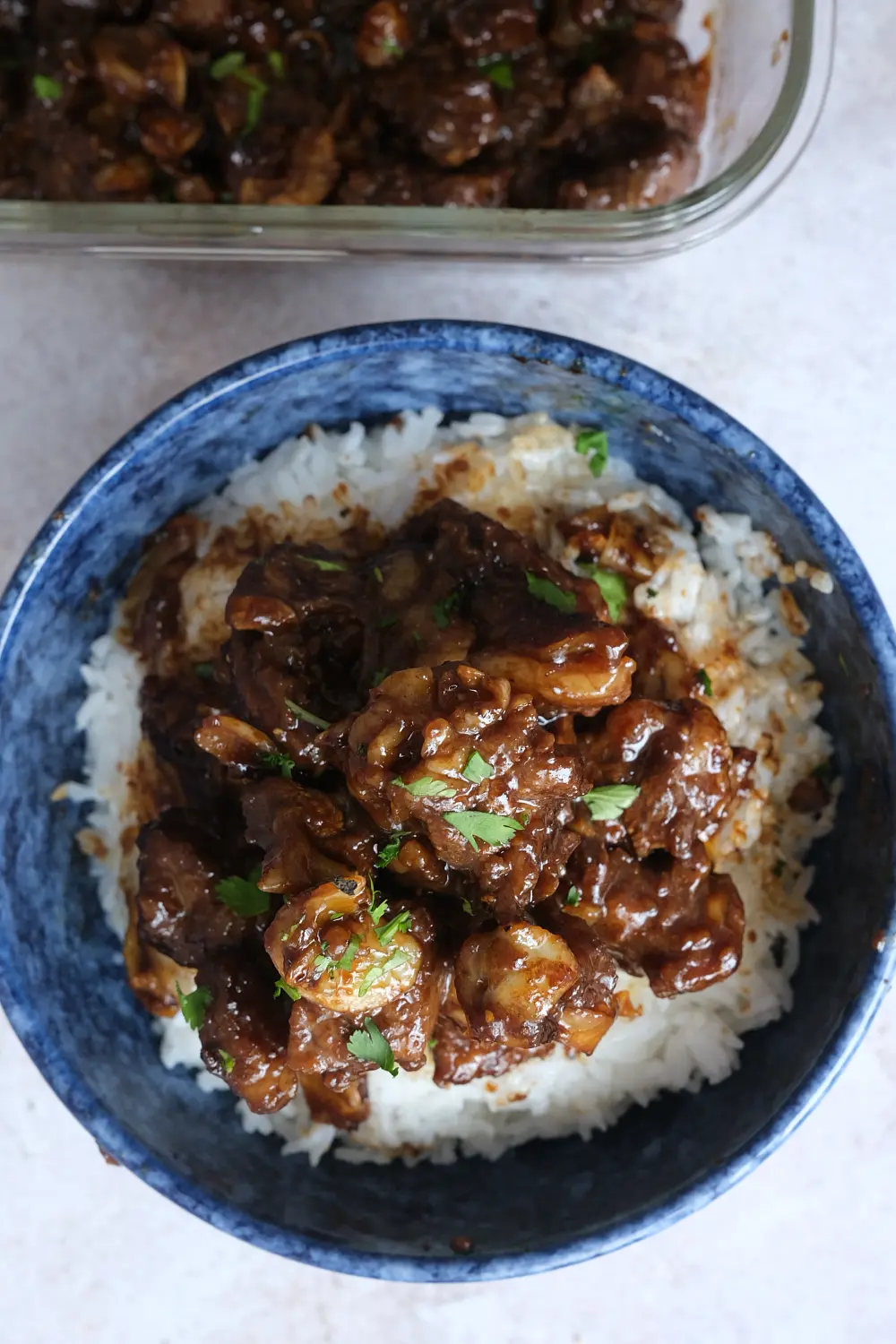 Filipino beef salpicao served over steamed white rice in a blue bowl.