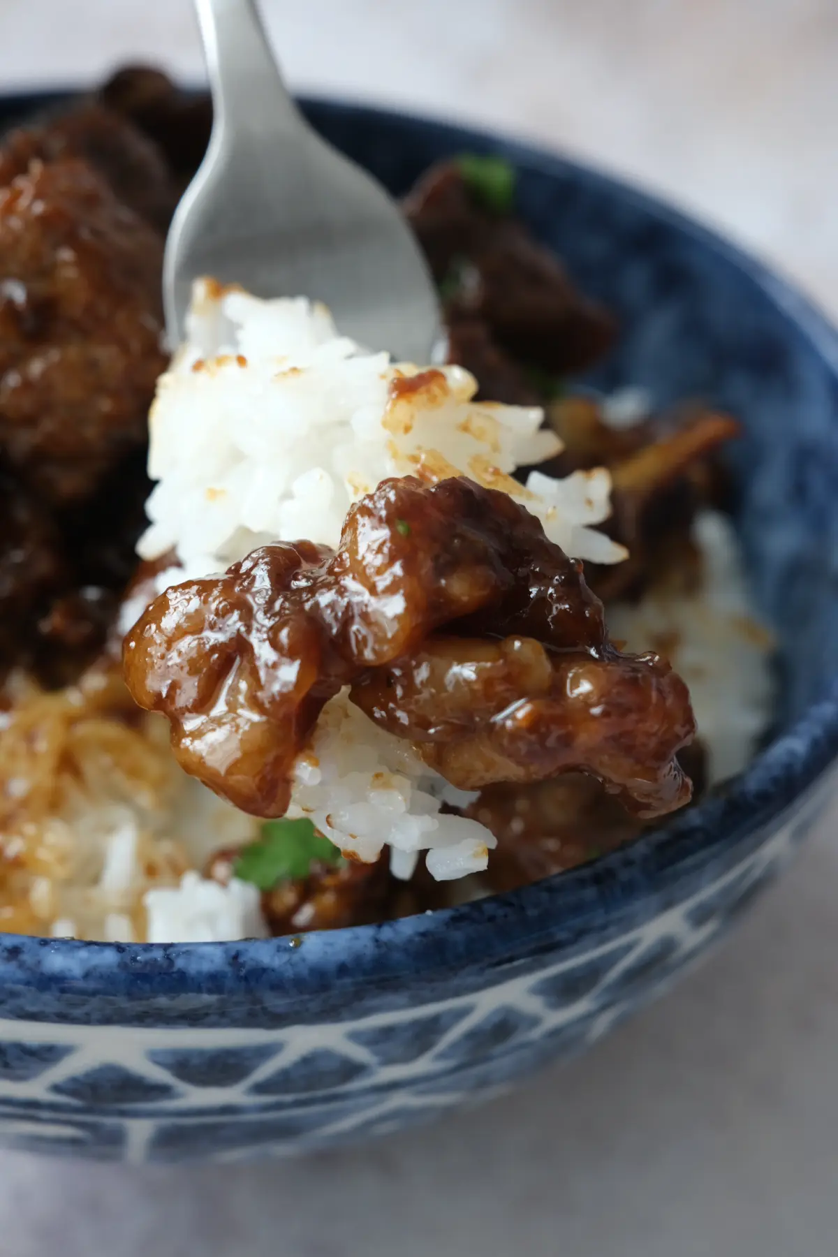 Forkful of beef salpicao and steamed rice coated in rich soy garlic sauce.