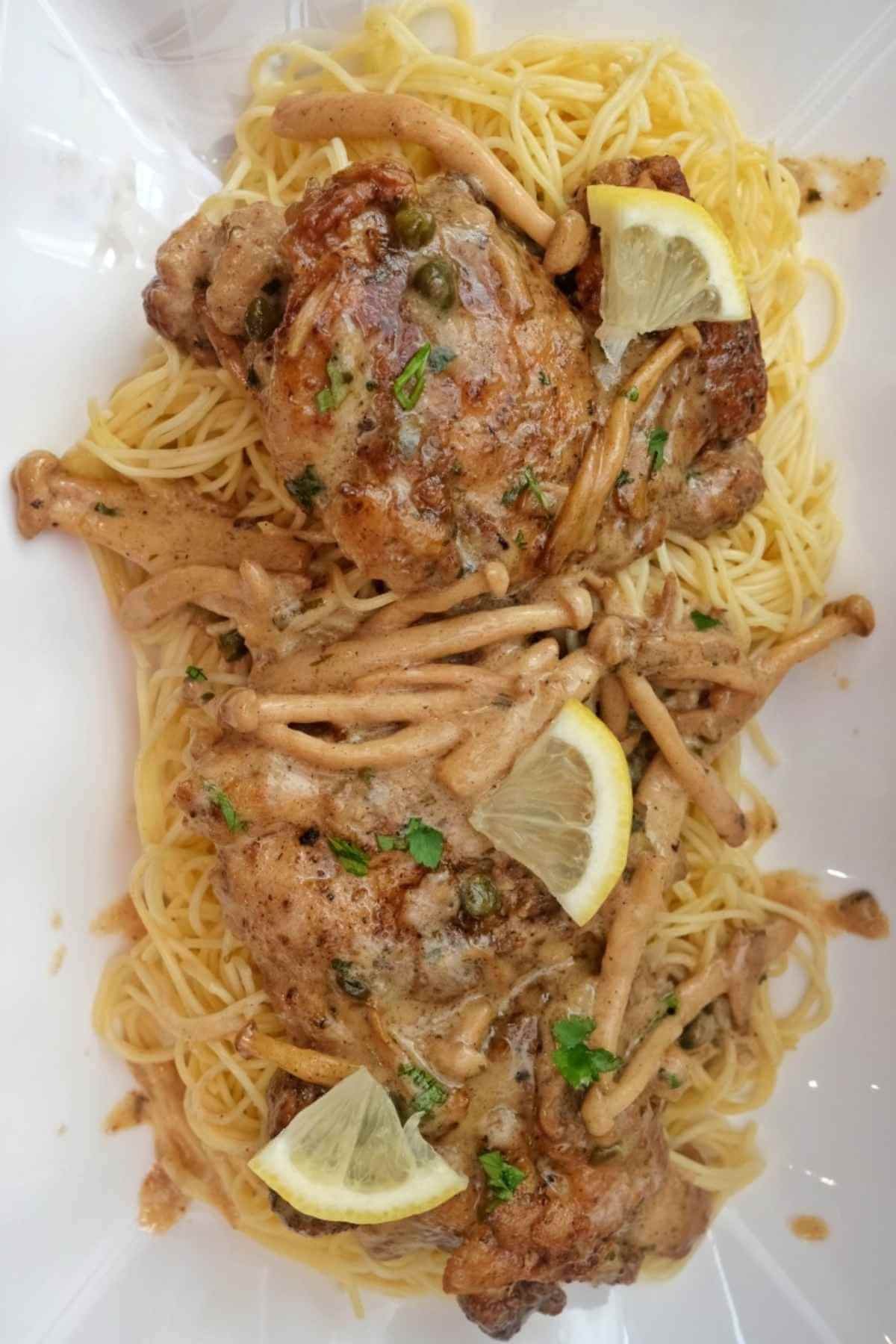 Close up of chicken piccata with mushrooms and capers in a rich creamy sauce.