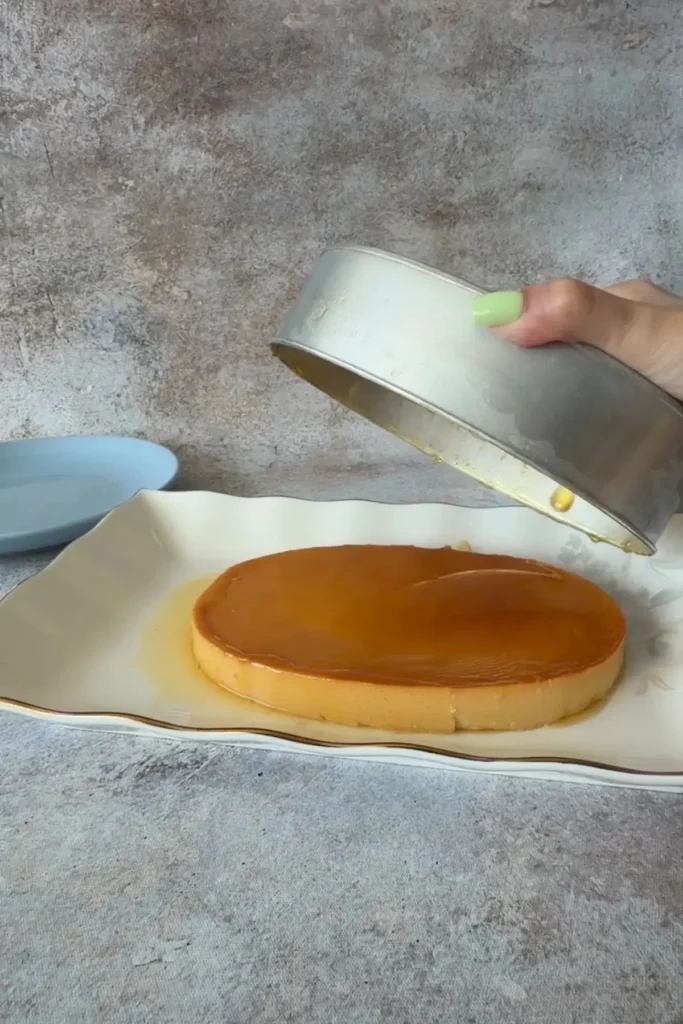 Leche flan inverted onto a serving platter with caramel sauce flowing over the top.