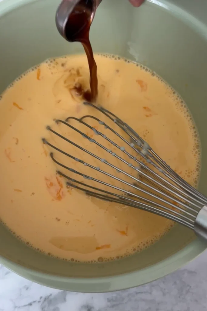 Vanilla extract poured into the custard mixture.