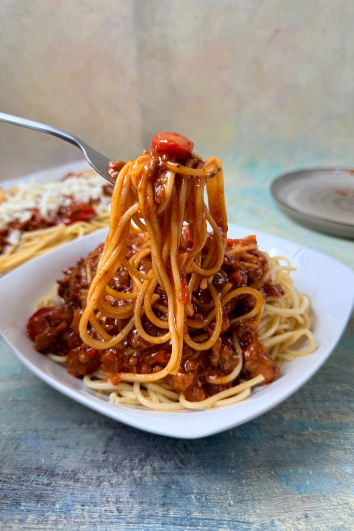 Filipino spaghetti in a bowl, with a fork lifting a portion.