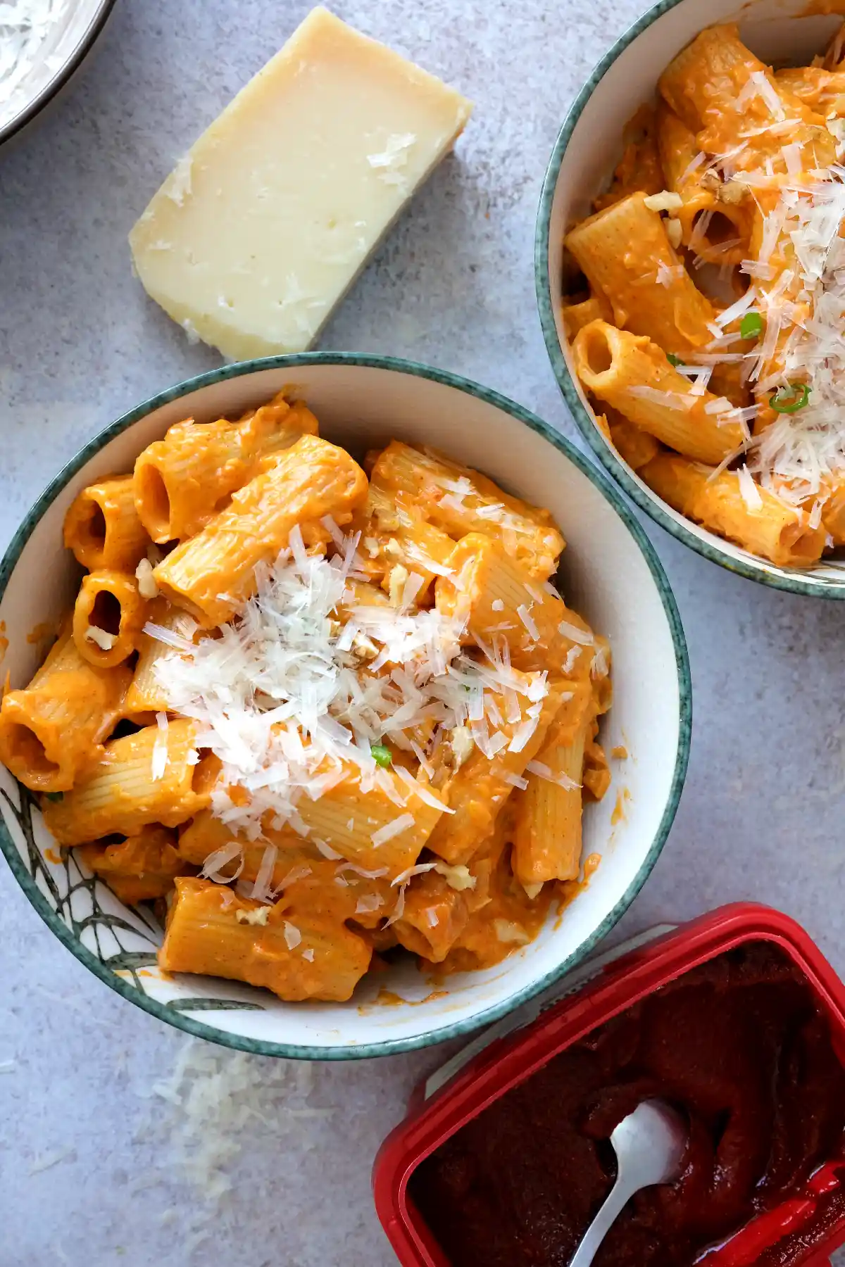 Two bowls of creamy gochujang pasta topped with Parmesan and chopped walnuts.