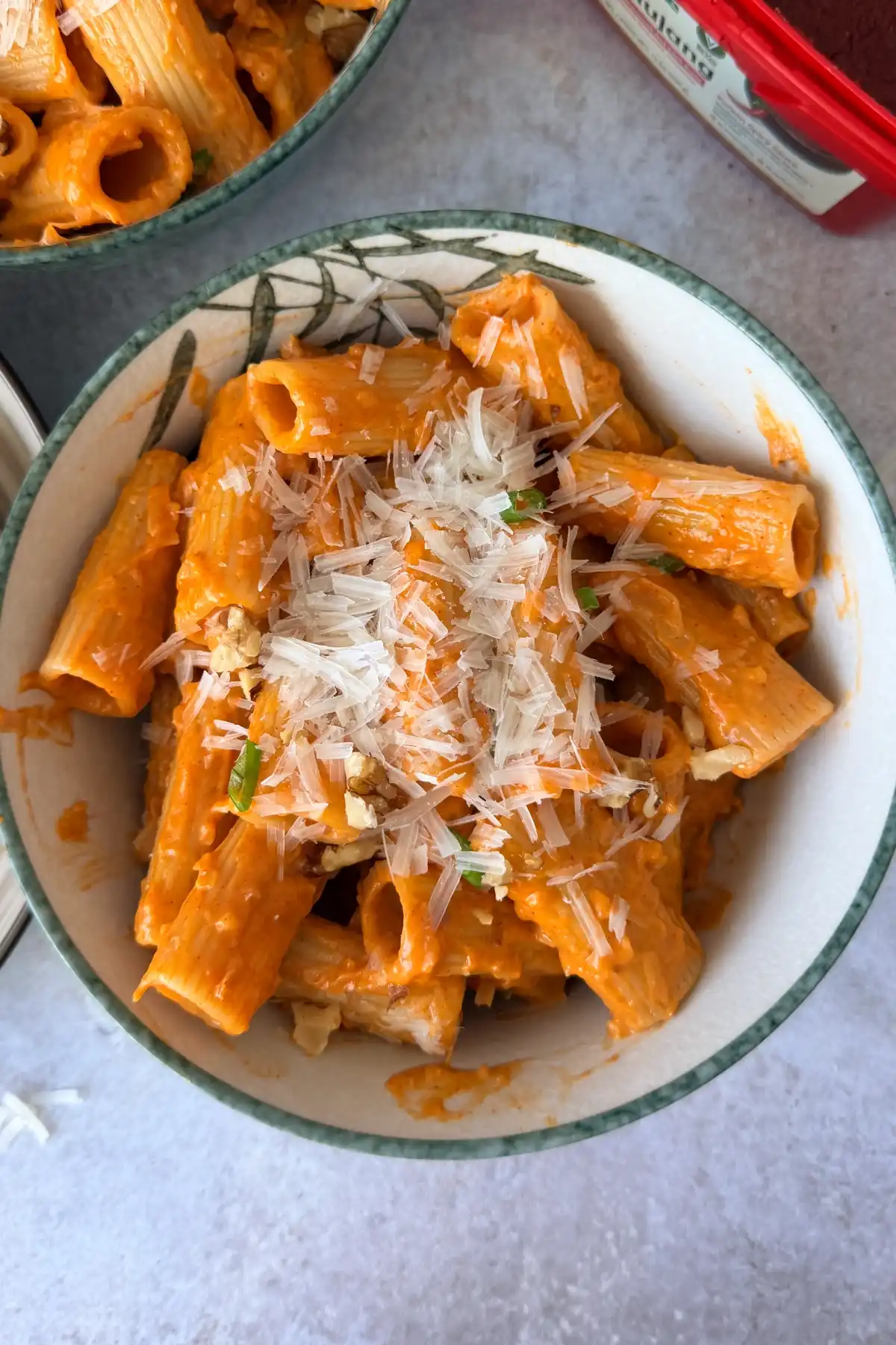 Creamy gochujang pasta in a bowl topped with freshly grated Parmesan and chopped walnuts.