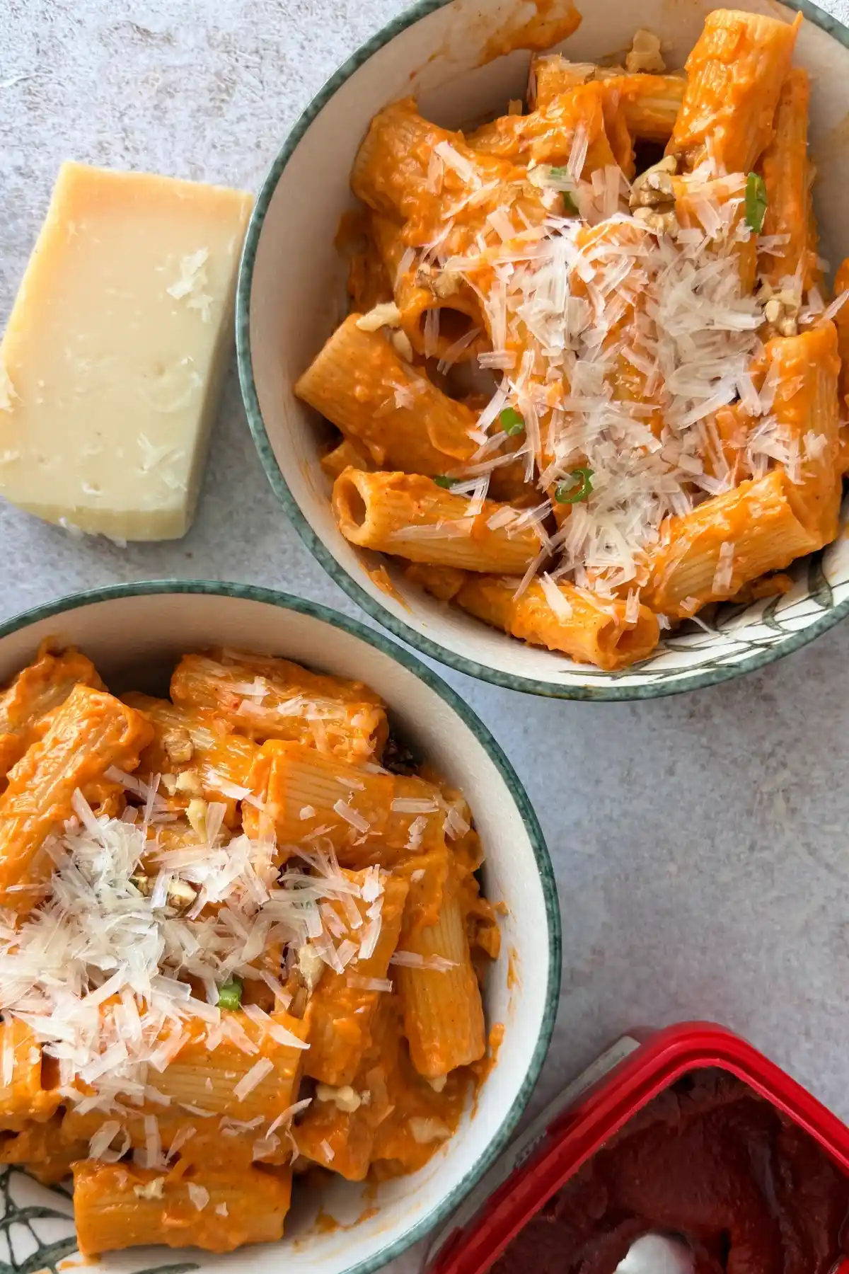 Block of Parmesan cheese with freshly grated cheese beside creamy gochujang pasta.