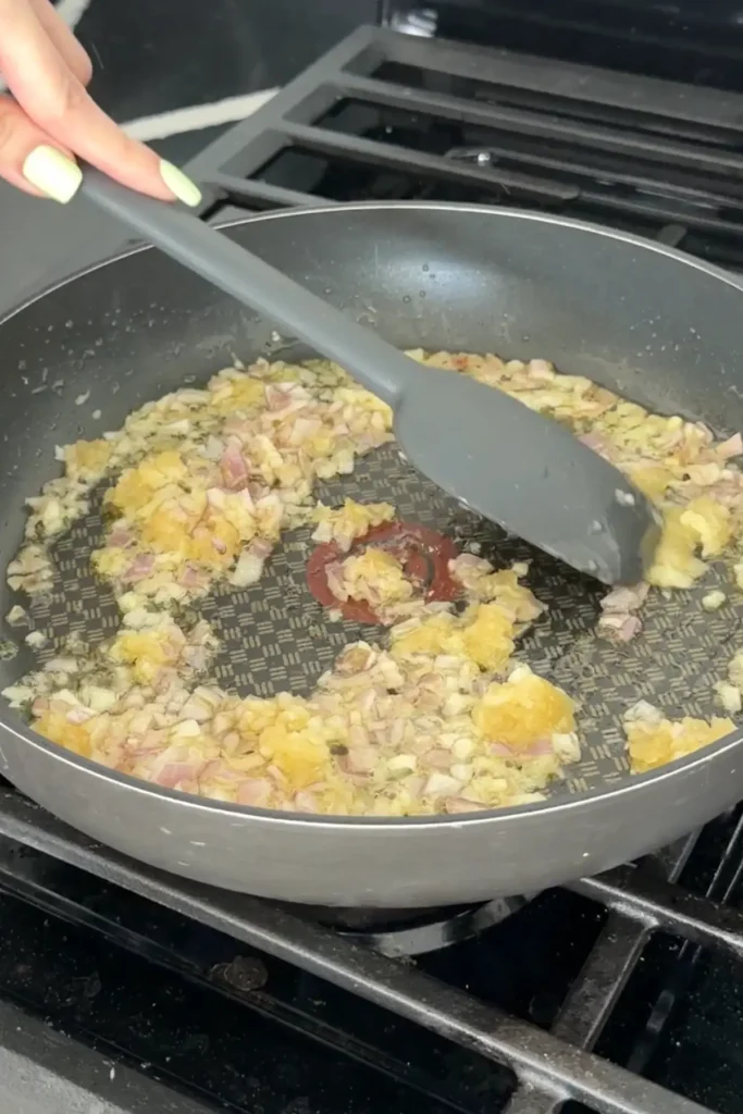 Minced garlic and onion sautéing in butter in a skillet until soft and fragrant.
