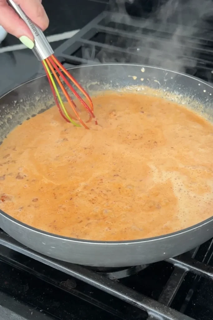Creamy gochujang sauce simmering in a skillet until smooth and slightly thickened.