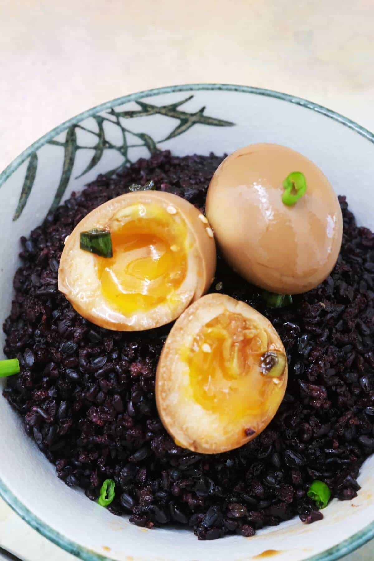 Soft-boiled soy-marinated eggs with golden centers on a bowl of black rice