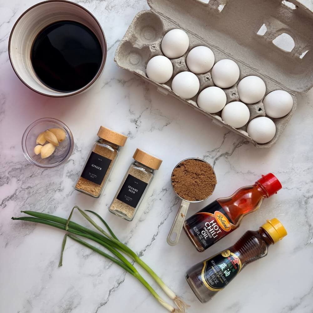 Ingredients for Korean mayak eggs: soy sauce, eggs, garlic, ginger, sesame seeds, chili oil, and green onions