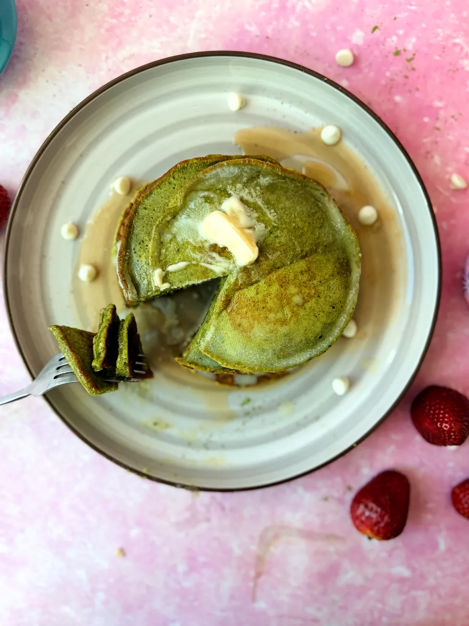 Overhead shot of partially sliced matcha pancakes with butter and syrup