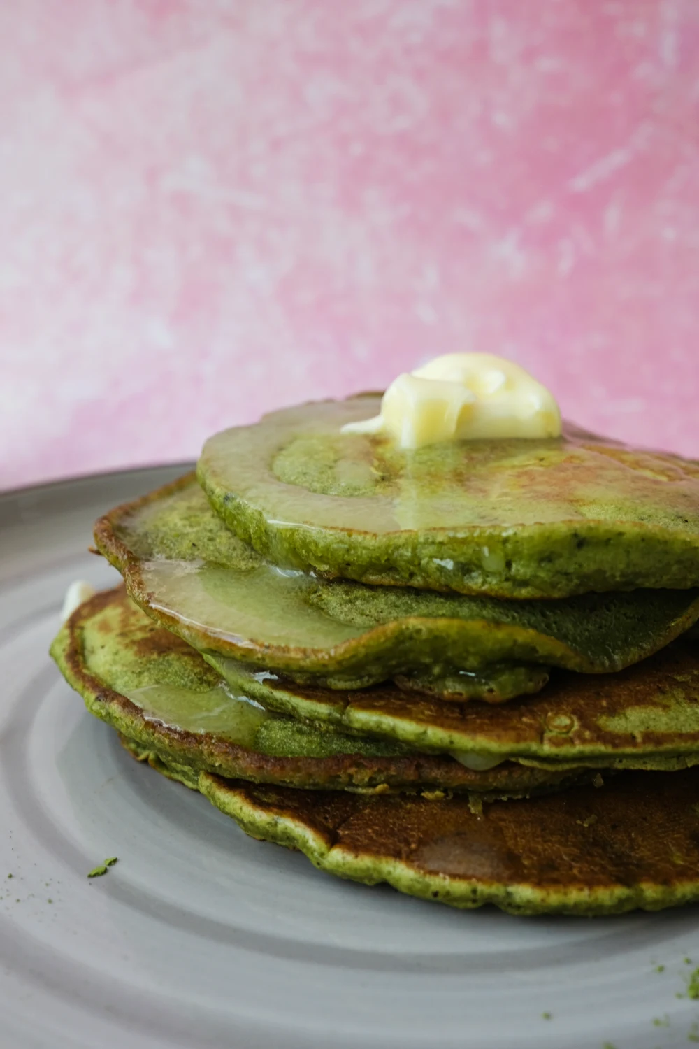 Close-up of fluffy matcha pancakes soaked in maple syrup