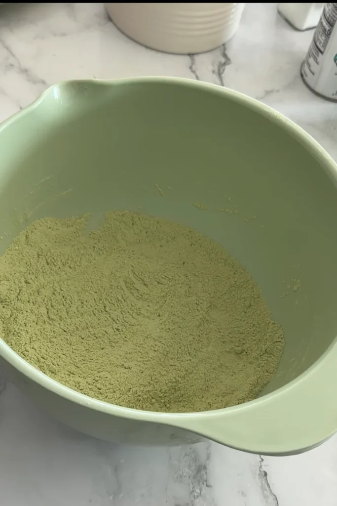 Whisked matcha pancake batter in mixing bowl, smooth and light green with small specks of matcha.