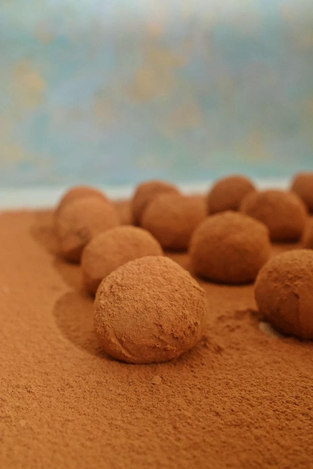Milk chocolate truffles arranged over a layer of cocoa powder.