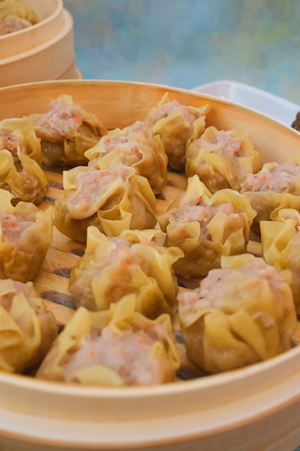 Steamed pork siomai in bamboo steamer with chili garlic dipping sauce.