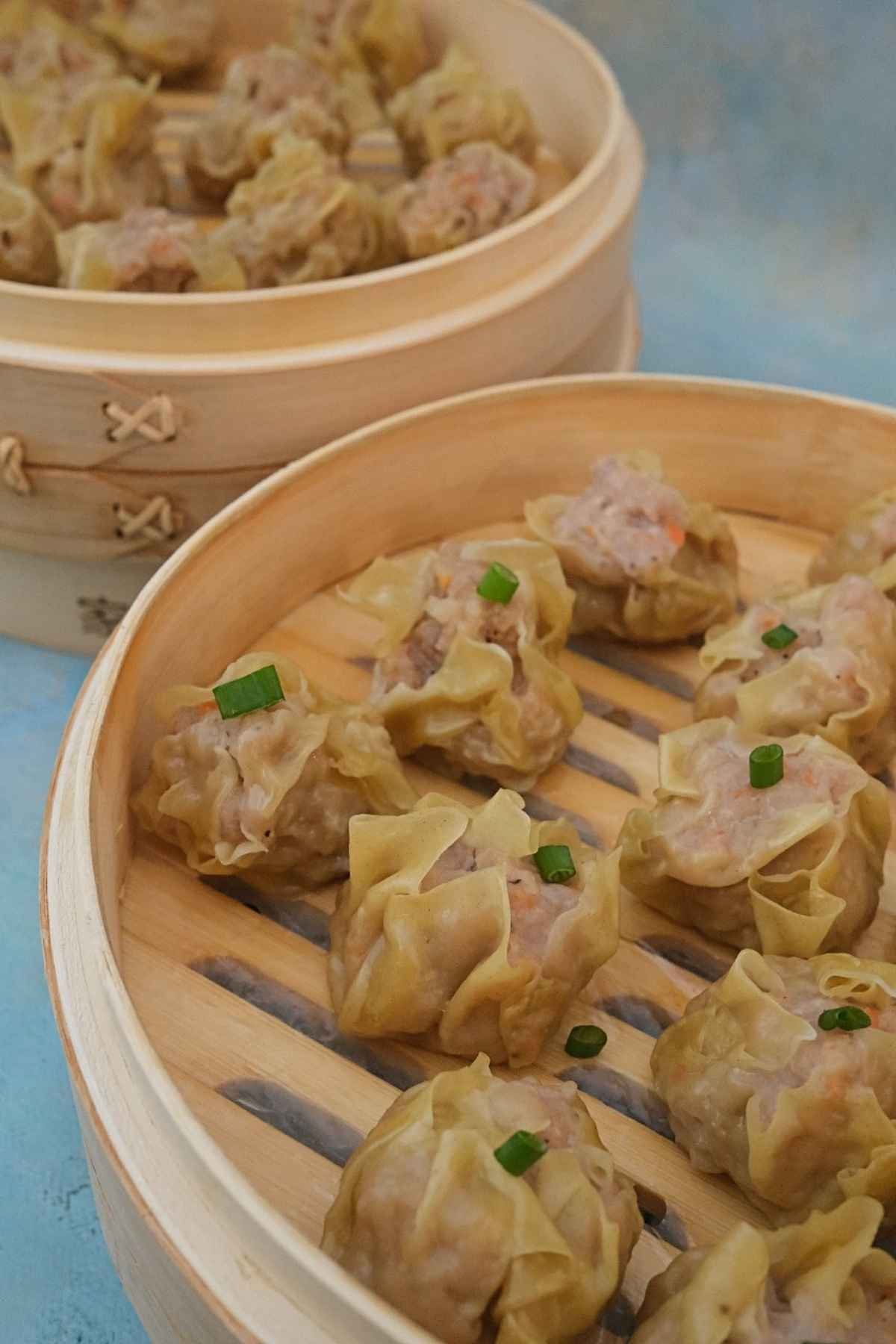 Freshly steamed pork siomai arranged in 2 bamboo steamer baskets.
