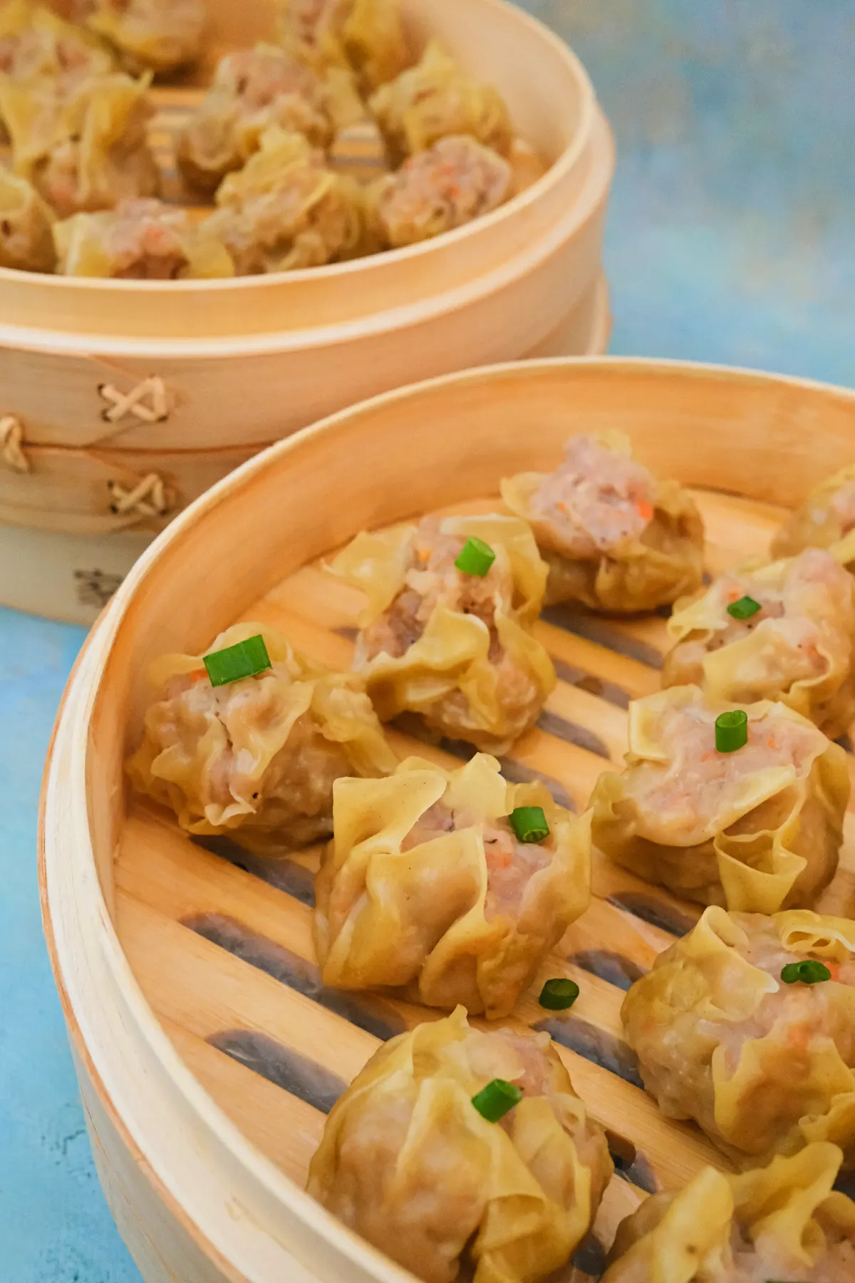 Freshly steamed pork siomai arranged in 2 bamboo steamer baskets.
