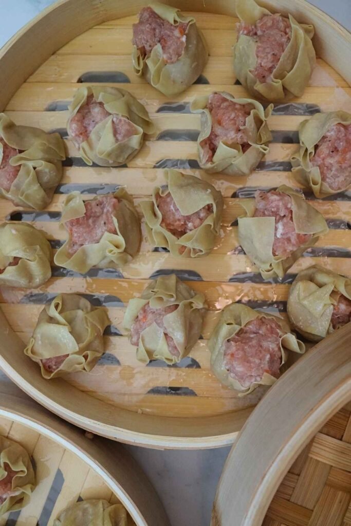 Uncooked pork siomai arranged on a baking sheet before steaming.