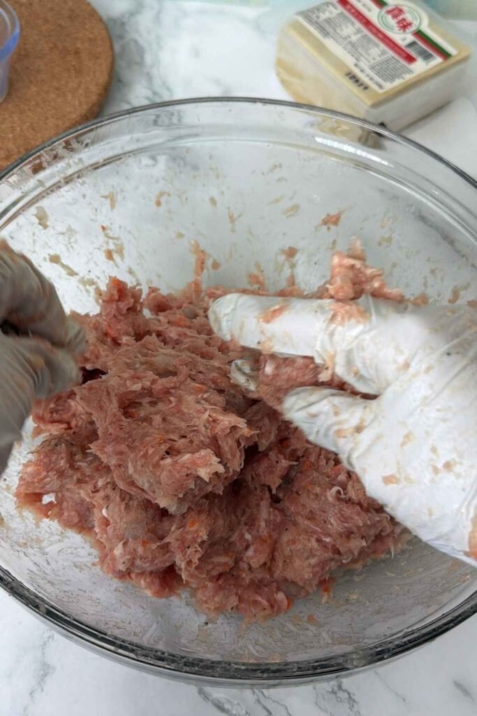 Mixing pork and shrimp filling by hand until sticky and well combined.