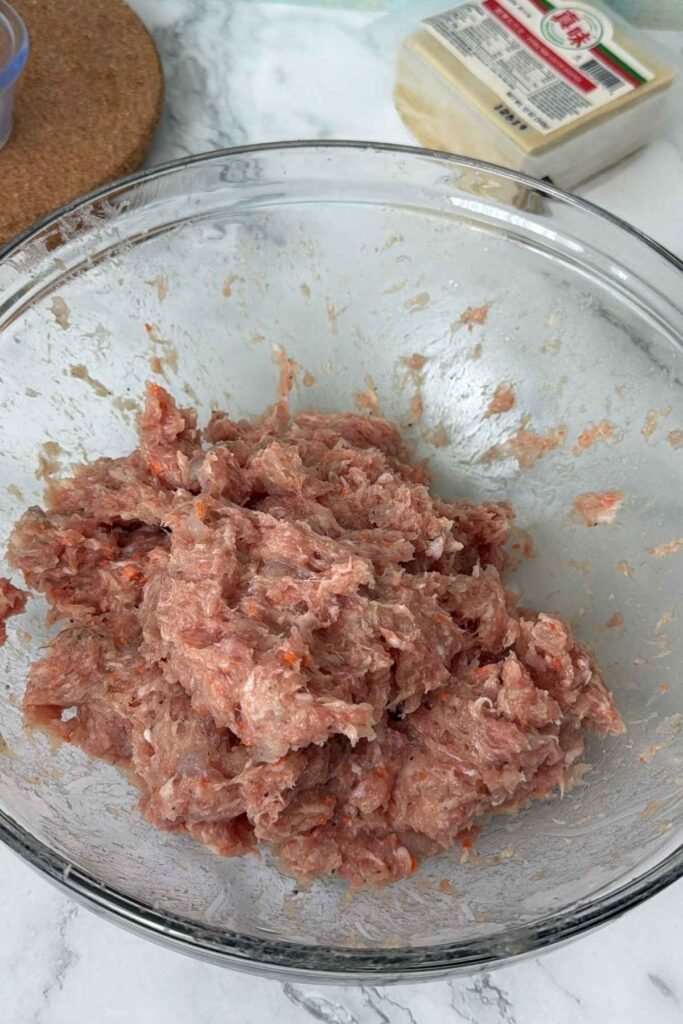 Ground pork and shrimp mixture fully combined in a mixing bowl.