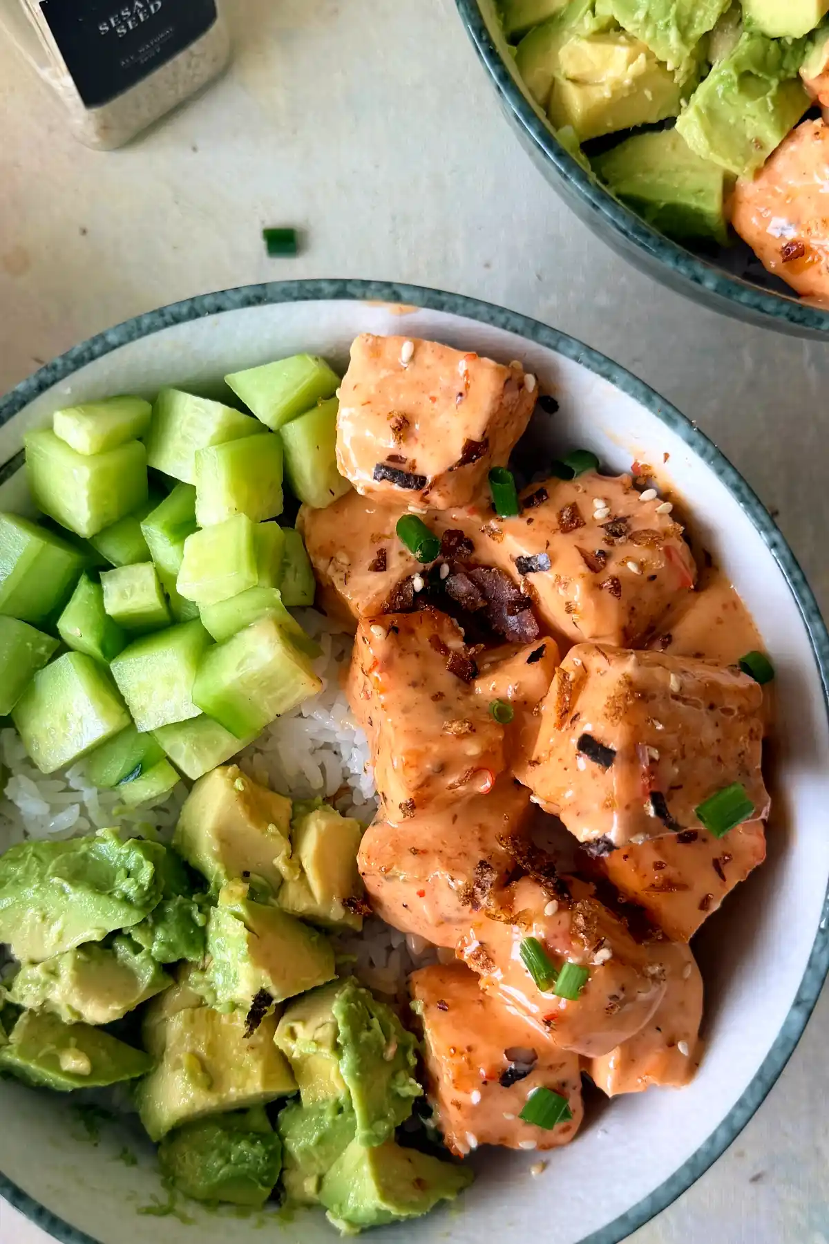 Salmon rice bowl with creamy bang bang salmon bites, diced cucumber, avocado, and white rice.