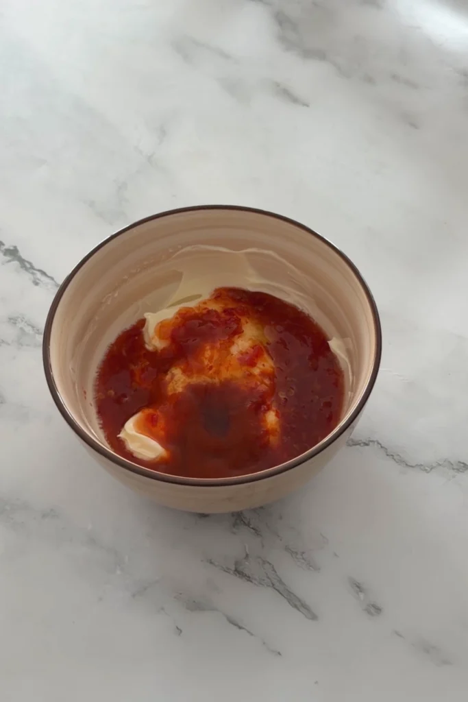 Mayonnaise and sweet chili sauce in a bowl before mixing to make bang bang sauce.