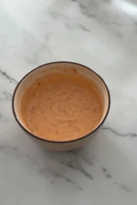 Creamy homemade bang bang sauce mixed until smooth and lightly orange.