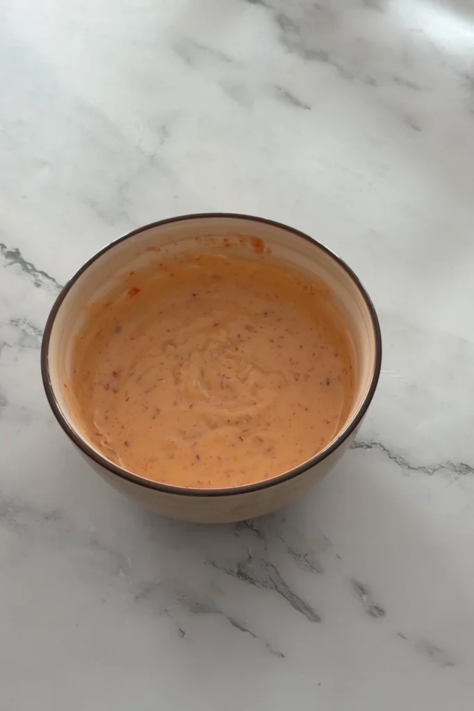 Creamy homemade bang bang sauce mixed until smooth and lightly orange.