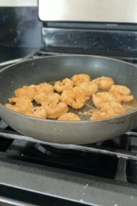 Crispy fried shrimp cooking in a pan until golden brown