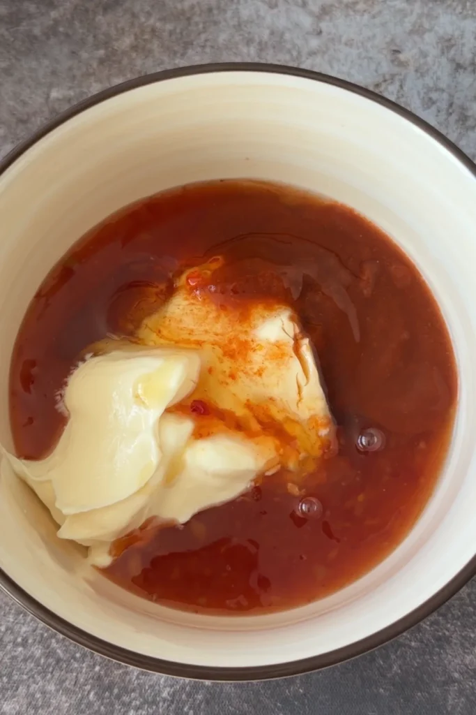 Ingredients for bang bang sauce including mayonnaise, sweet chili sauce, and sriracha in a bowl