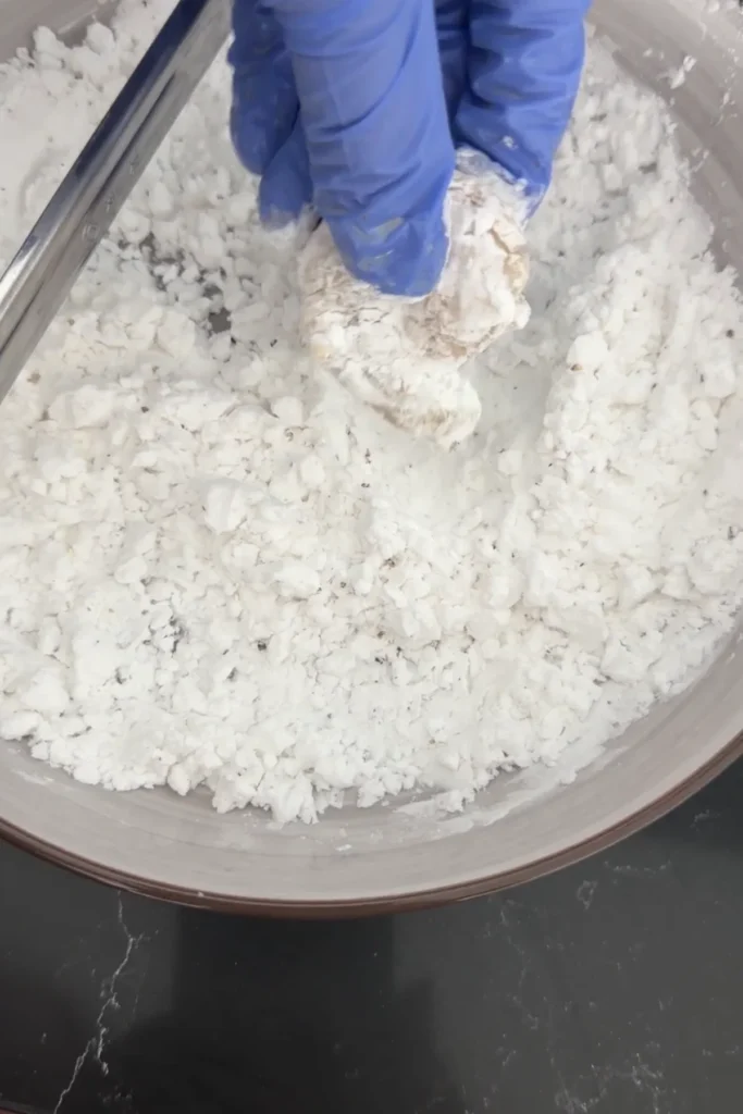 Hand dredging shrimp in seasoned potato starch mixture for crispy coating