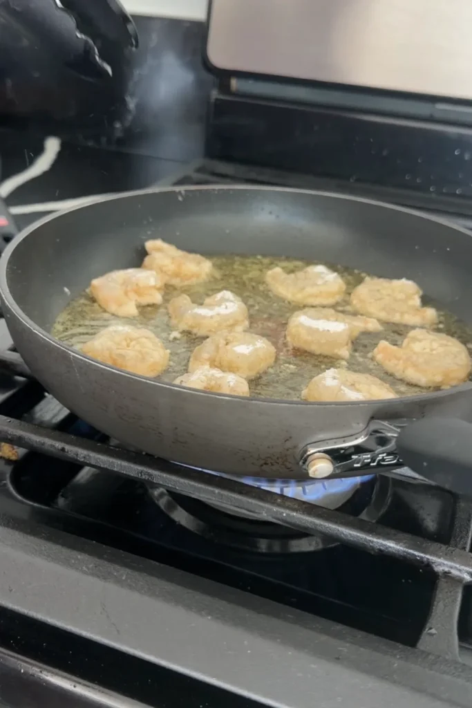 Shrimp frying in hot oil in a skillet until lightly golden and crispy
