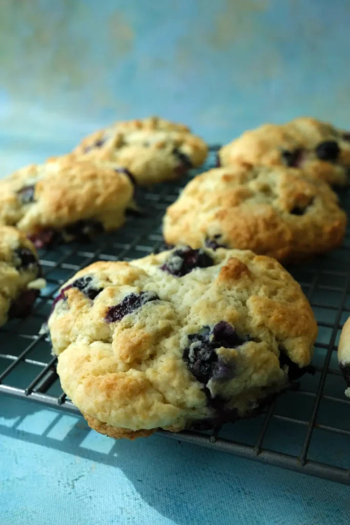 Freshly baked blueberry biscuits on a wire rack.