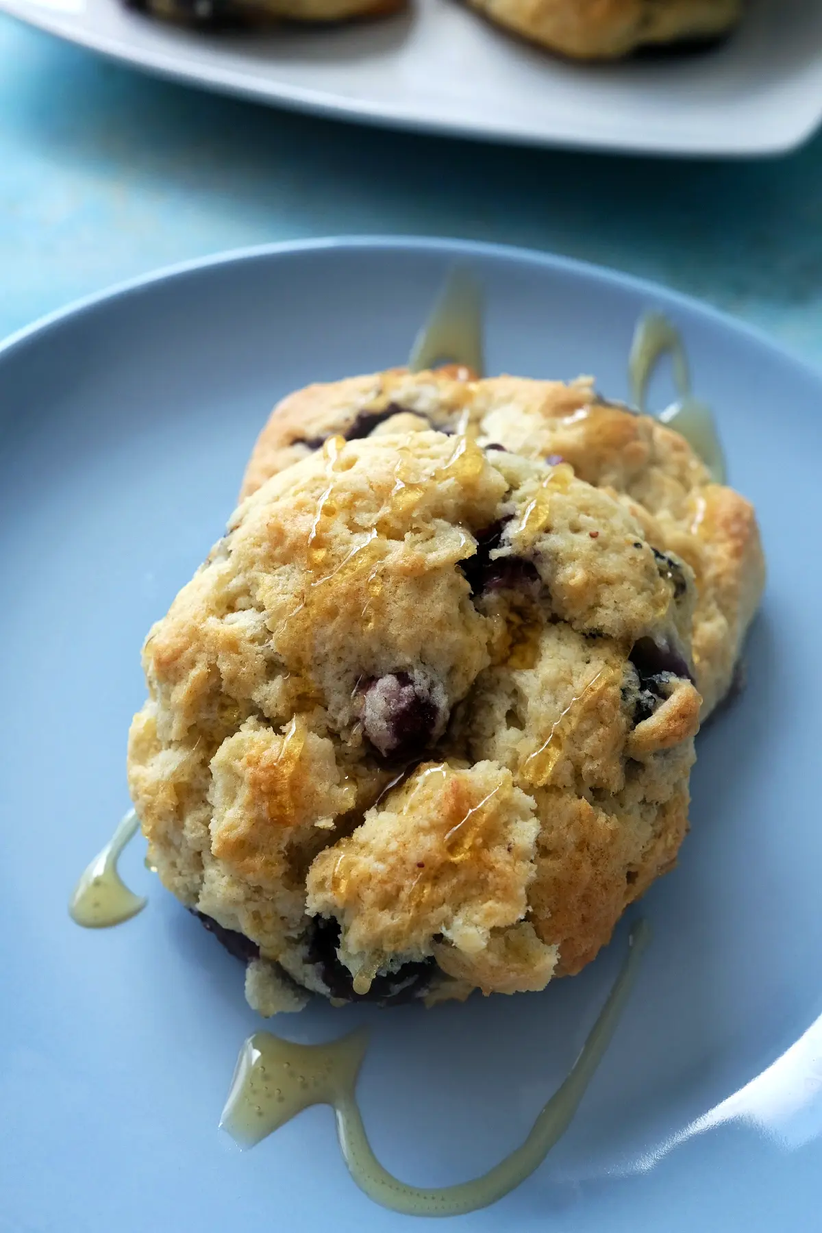 Two homemade blueberry biscuits drizzled with honey.