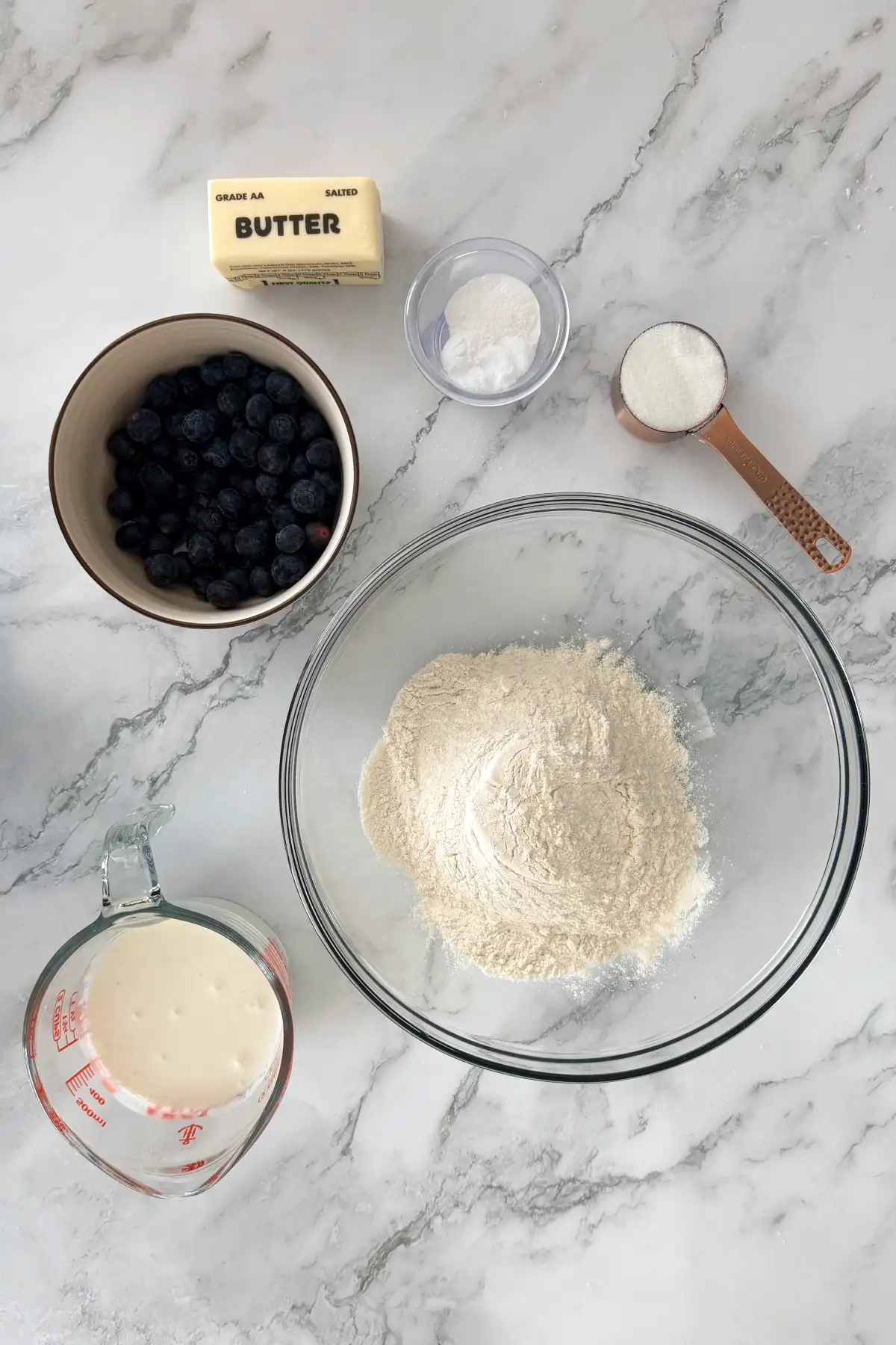 Ingredients for blueberry biscuits: flour, butter, salt, baking powder, baking soda, blueberries, cream, and sugar.