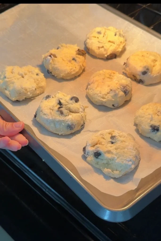 Unbaked blueberry biscuits on a parchment-lined baking sheet ready for the oven.