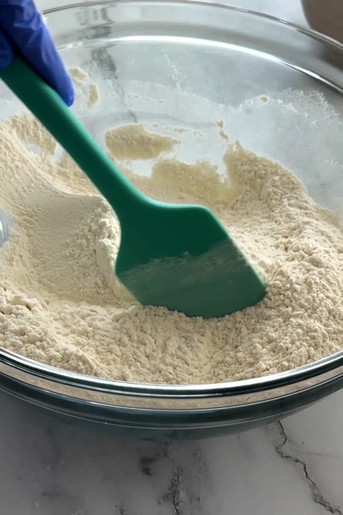 Mixing flour, sugar, and leavening for homemade blueberry biscuits.
