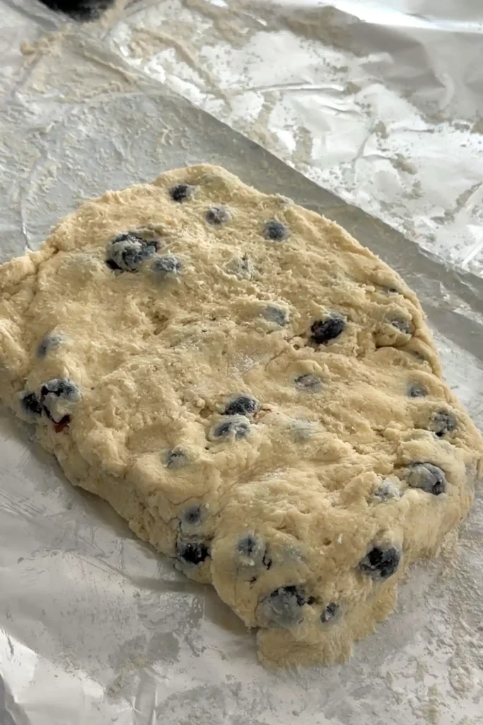 Blueberry biscuit dough patted into a rectangle on floured surface.