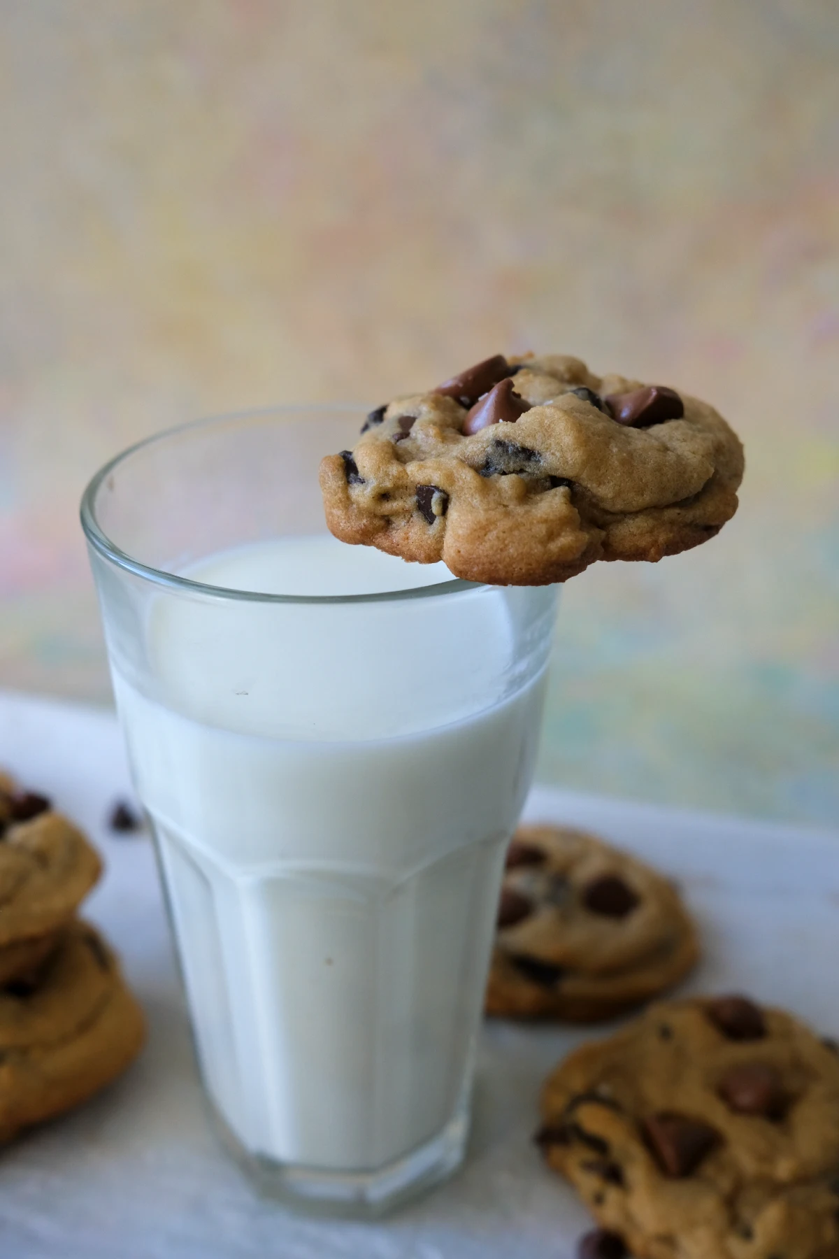 Brown sugar chocolate chip cookie balanced on the rim of a glass of milk.