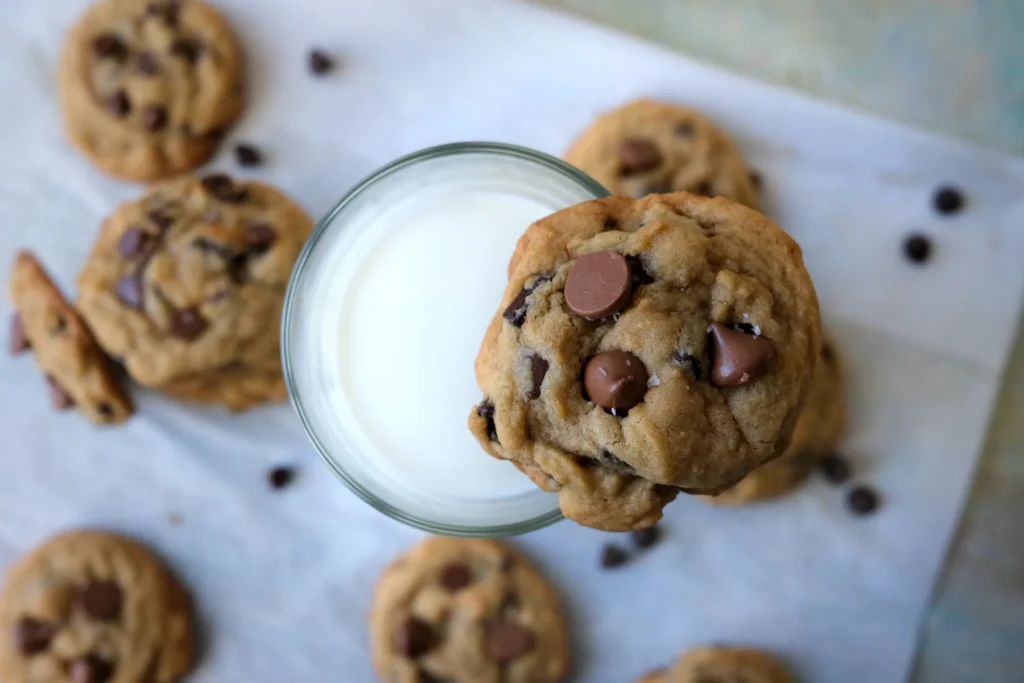 Brown sugar chocolate chip cookie balanced on the rim of a glass of milk.
