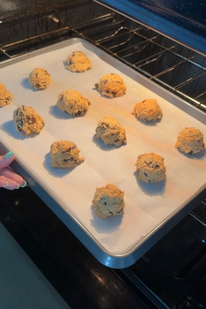 Tray of chocolate chip cookie dough balls placed into oven to bake.