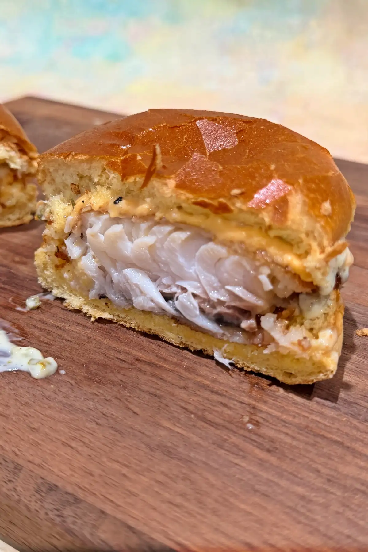 Close-up of the inside of a crispy cod fish sandwich with flaky fish and toasted brioche bun.