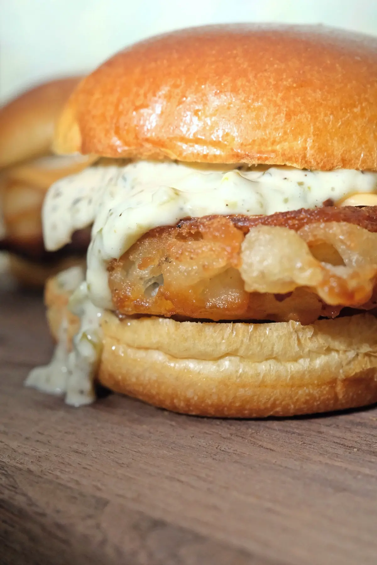 Close-up of a crispy fried cod fish sandwich showing the crunchy batter and tartar sauce.