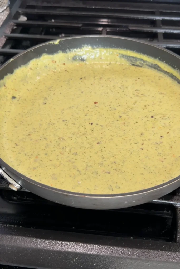 Rich and thick creamy pesto sauce simmering in pan