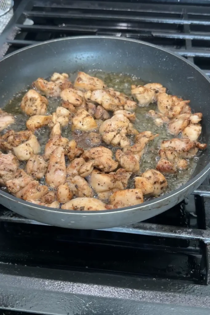 Golden brown chicken pieces searing in a pan with crispy edges