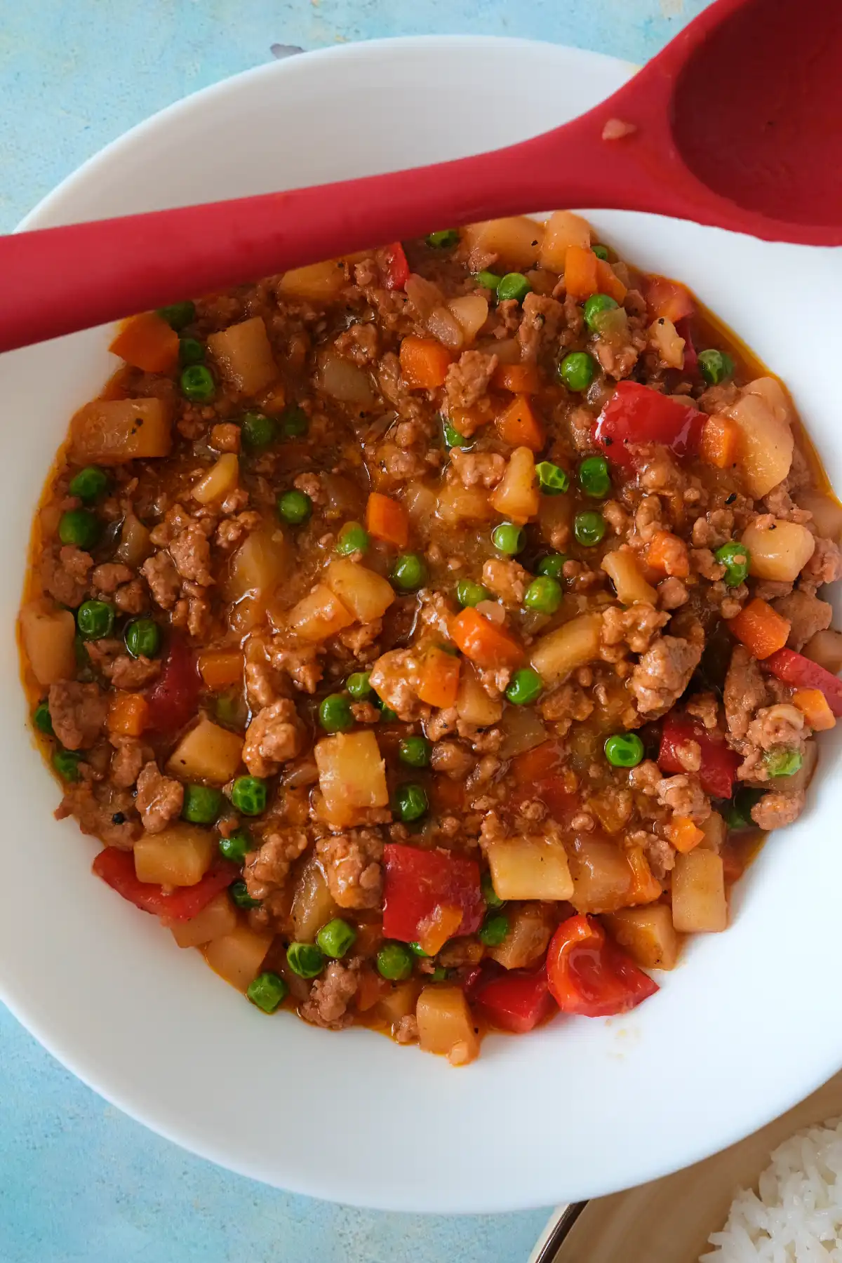Filipino picadillo with ground pork, potatoes, carrots, peas, and bell peppers in tomato sauce.