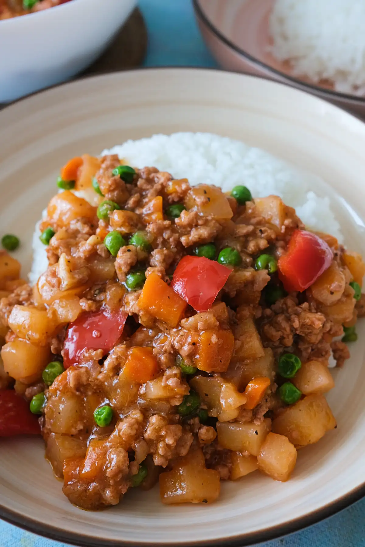 Filpino picadillo with potatoes, carrots, peas, and red bell peppers spooned over steamed rice.