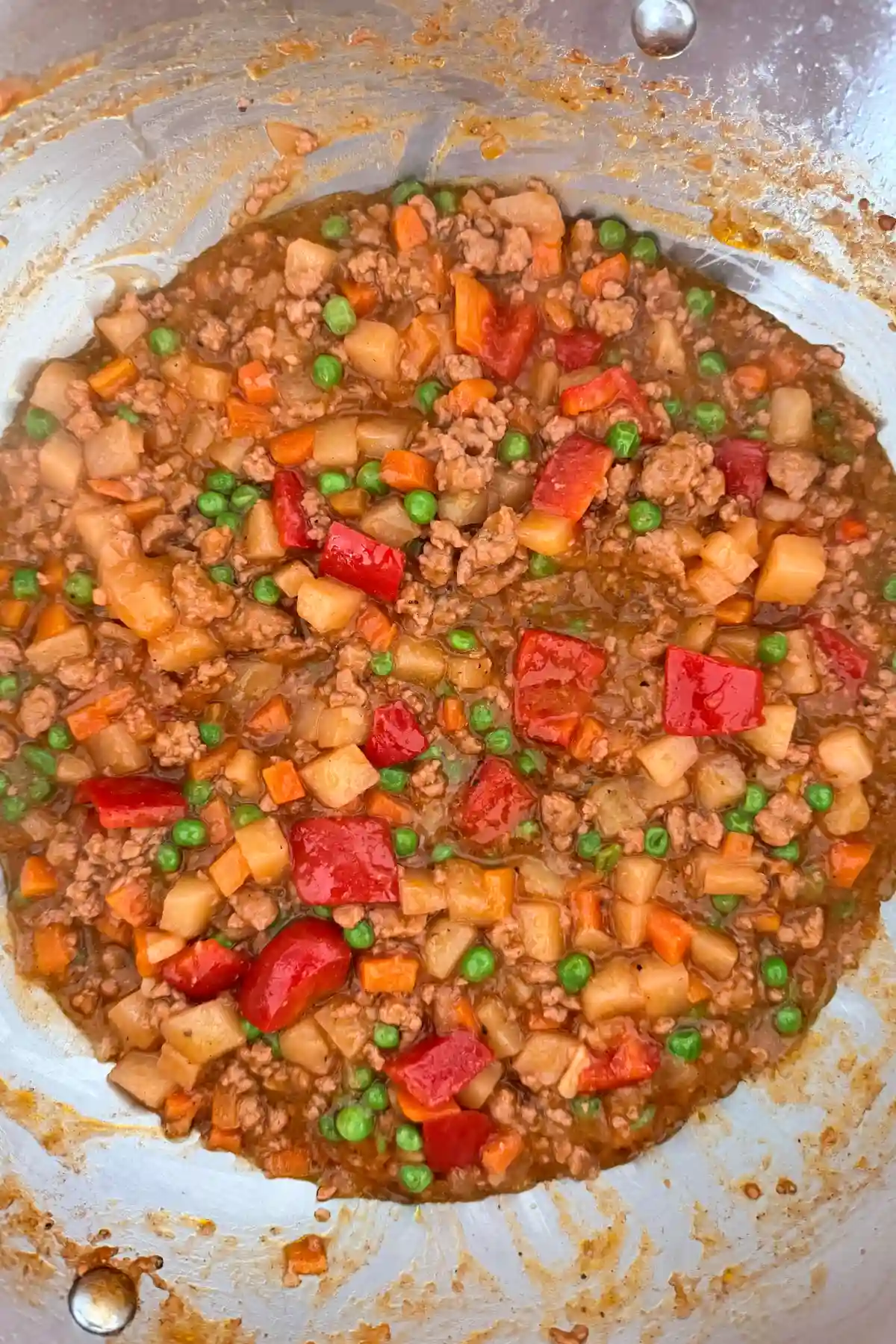 Finished Filipino pork picadillo with ground pork, potatoes, carrots, peas, and bell peppers in tomato sauce.